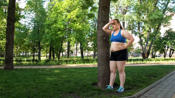 肥満に苦しんでいる公園でハード トレーニング後休んで脂肪の若い女性 — ストック写真