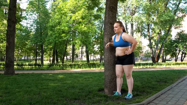 Obese woman suffering from muscle pain after workout in park, active lifestyle