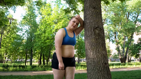 Lihava Nainen Näyttää Väsyneeltä Harjoittelun Jälkeen Puistossa Nojaten Puuhun Motivaatio — kuvapankkivalokuva
