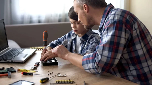 Caring father teaching his little son to repair hard disk drive at home, hobby