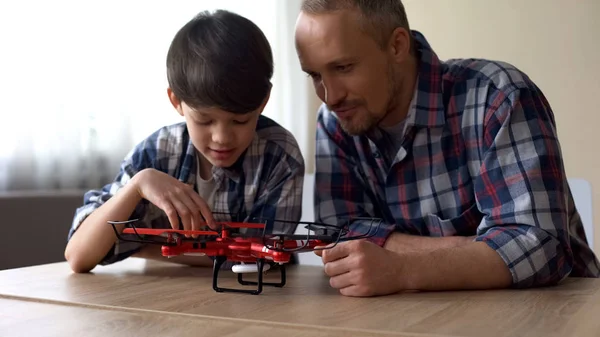 好奇的父亲和小儿子在家里检查新的 Quadrocopter — 图库照片