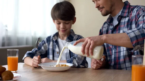 Отец Наливает Молоко Тарелку Кукурузными Хлопьями Сын Папа Завтракают — стоковое фото