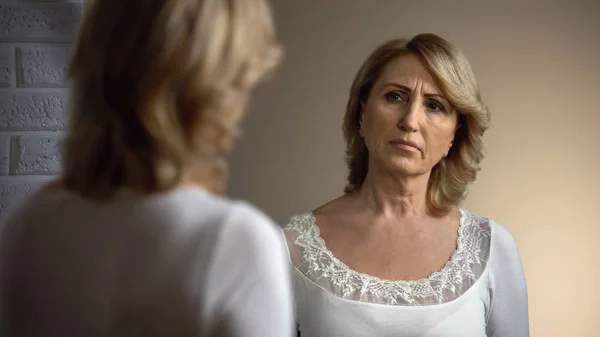 問題の鏡で反射を見て白いドレスで落ち込んでいる老婆 — ストック写真
