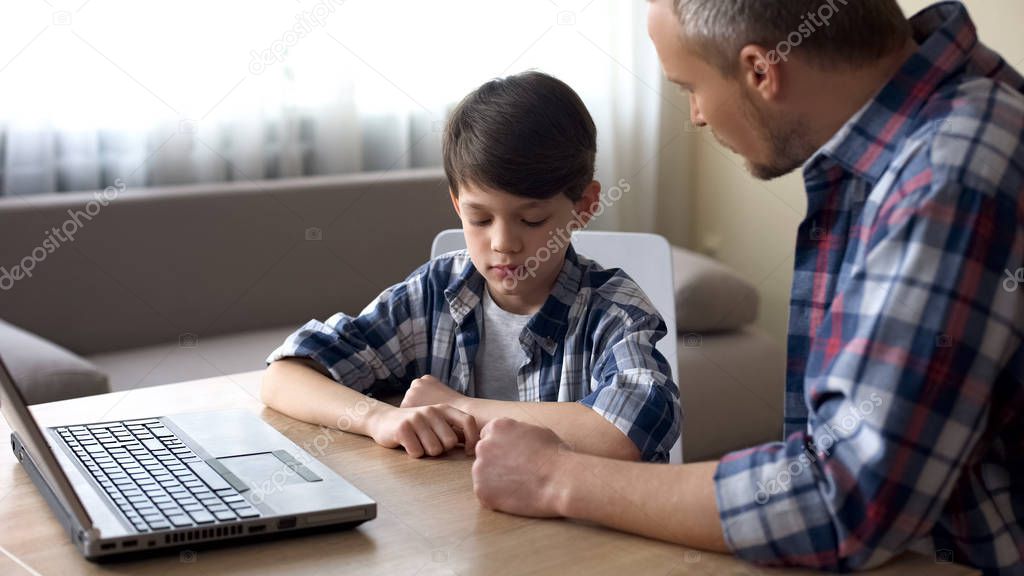 Strict father scolding his little son for computer addiction, family problem