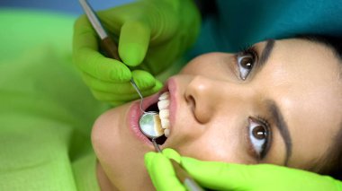 Hastalar diş, profesyonel çalışma, closeup incelemek için ayna kullanarak stomatologist