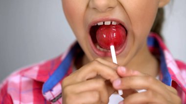 Sevimli küçük kız lolipop şeker etkisini dişlerde, diş bakımı ısırmaya çalışıyor