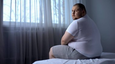 Seyir fotoğraf makinesi, depresyon, güvensizliği evde, yatakta oturan üzgün şişman adam
