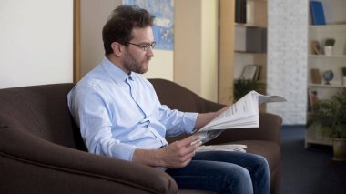Kanepe ve okuma gazete evde, sabah ritüeller oturan orta yaşlı erkek