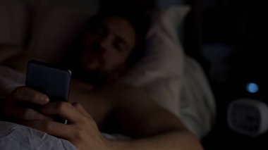 Uykusuz erkek yatakta, sohbet smartphone, gadget bağımlılığı, uykusuzluk