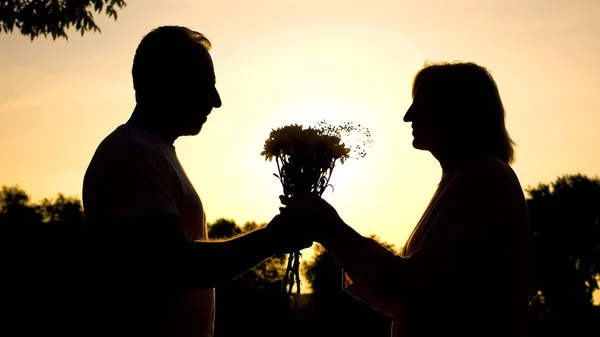 Sylwetka Szczęśliwa Para Posiedzeniu Zachód Mąż Przedstawiając Kwiaty Dniu — Zdjęcie stockowe