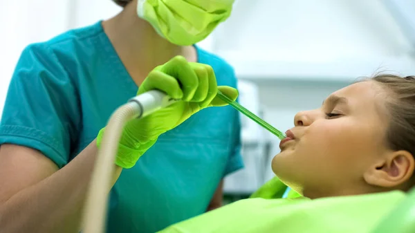 Dentista Femenina Usando Eyector Saliva Adolescente Sentada Silla Frunciendo Ceño —  Fotos de Stock