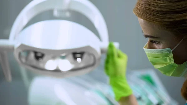 整形外科 美容の前にライトを調整した女性看護師 — ストック写真