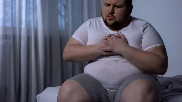 Overweight man suffering from chest pain, high blood pressure, cholesterol level