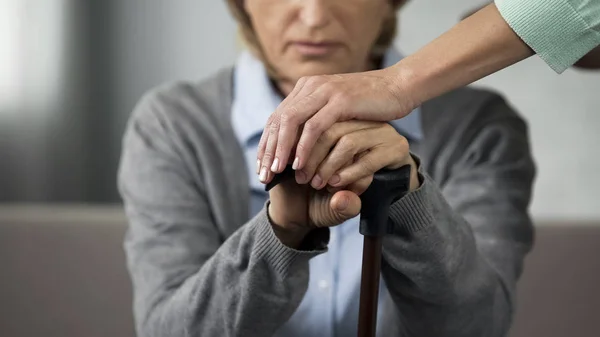 老人退休的女士坐在沙发上 年轻的女人触摸她的手仔细 — 图库照片