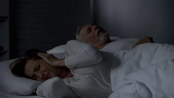 老年女性按手对耳朵不能睡觉 男人打呼噜在床上 — 图库照片