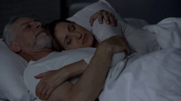 ベッドで横になっていると強力な結婚 男性の胸の上に横たわる女性を抱き締めるシニア カップル — ストック写真