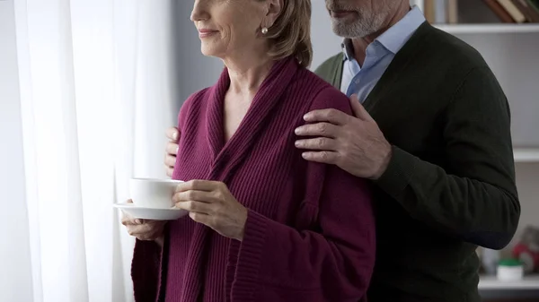 Aging Lady Standing Cup Tea Window Loving Man Hugging Her — Stock Photo, Image