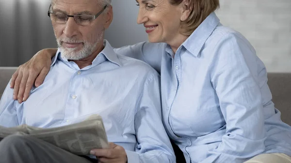 Jubilado Marido Leyendo Periódico Sofá Mujer Lado Abrazarlo Amor — Foto de Stock