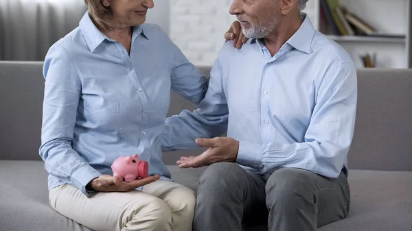 老年丈夫和妻子在沙发上拿着存钱罐 可靠的存款 — 图库照片