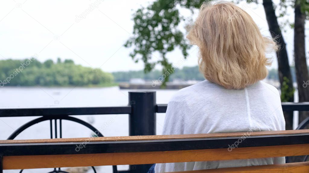 Aged female looking at river, thinking of life, countryside tranquility, rest