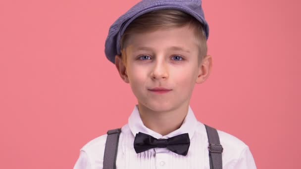 聪明的男孩在复古的衣服看着相机 孤立在粉红色的背景 — 图库视频影像