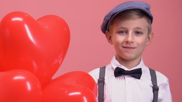 Schüchterner Kleiner Junge Mit Herzförmigen Luftballons Der Die Kamera Lächelt — Stockvideo