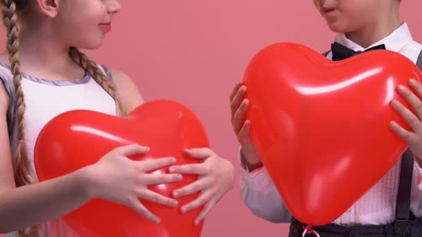Kalp Şeklinde Balonlar Tutarak Kamera Için Aşk Gülümseyen Küçük Çift — Stok video