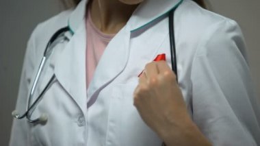 Kadın doktor tıbbi uyacak şekilde kırmızı kurdele bağlama AIDS bilinçlendirme kampanyası