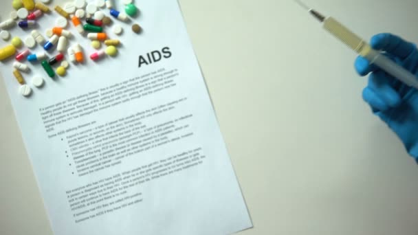 エイズの診断を紙に書かれた注射器 錠剤や錠剤のテーブルの上で手 — ストック動画