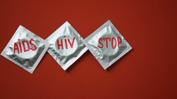 艾滋病 Hiv 停止的话和红色丝带在避孕套在红色背景 — 图库视频影像