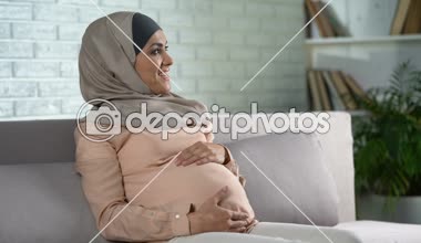 Karın hafifçe dokunma, ev, Doğum öncesi bakım dinlenme hijab mutlu hamile kadın