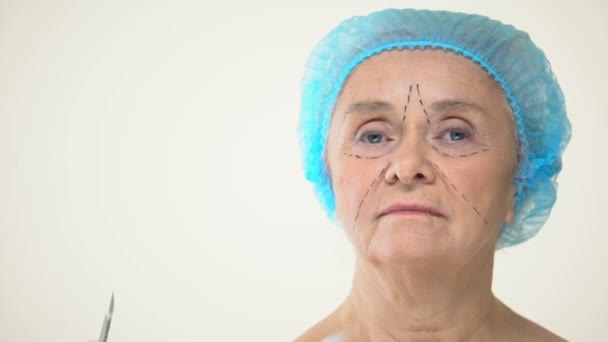 外科医生放置手术刀老化的女性病人的脸与标记 脸抬起 — 图库视频影像