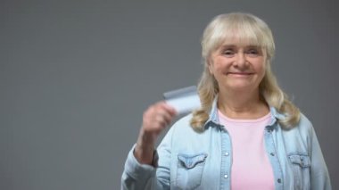 Memnun yaşlı Bayan banka müşteri gösteren kartı mali programı emekliler için