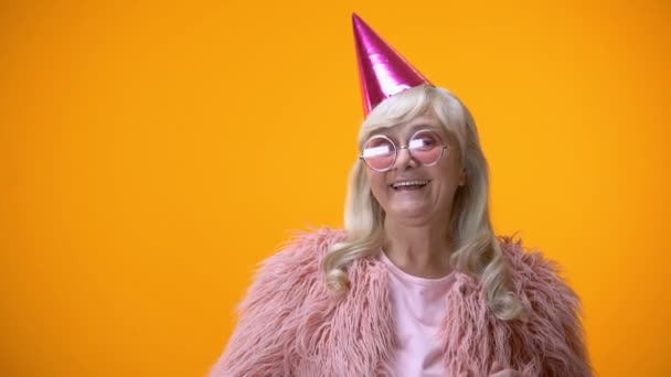 幸せな歳ピンクのコートと誕生日記念日を祝っている丸いメガネの女性 — ストック動画