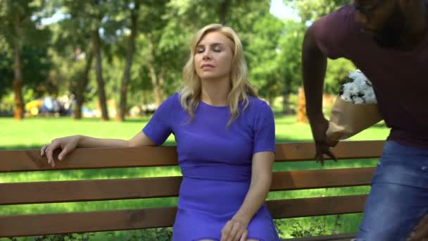 Hombre Negro Presenta Ramo Flores Triste Mujer Rubia Sentada Parque — Vídeo de stock