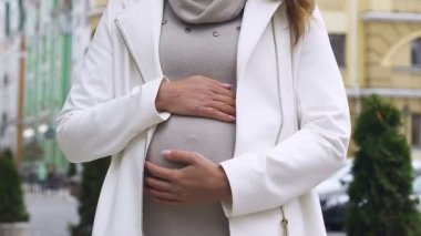 Göbek okşayarak ve kamera toplum Yardım'ı gülümseyen mutlu genç hamile bayan