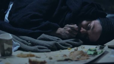 Aç serseri çöp ile yatan ve iştahla yemek orts, sığınak