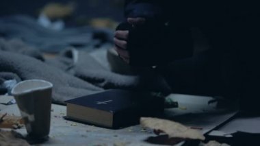 İncil ile katta oturan ve yardım için güçlü inanç dua evsiz dilenci