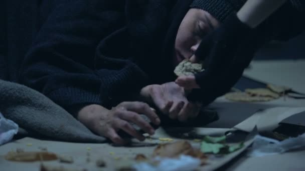 地面に横たわっている空腹のホームレスの女性にパン切れを与える人 — ストック動画