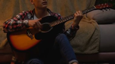 Solak genç rock ballad gitar ve şarkı şarkı evde tek başına oynarken