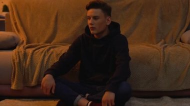 Evde tek başına oturan depresif genç, giyen hood, zorbalık kurbanı, sorun