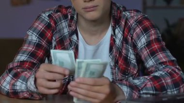 Genç çocuk kareli gömlekli sayma para, oturma ev masa, mali tasarruf