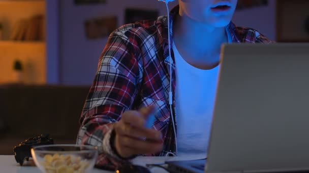 戴耳机的男性游戏玩家与网络朋友交谈 吃玉米片 — 图库视频影像