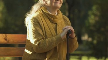 Baston Park, sosyal bakım ile engelliler için oturan mutlu yaşlı kadın