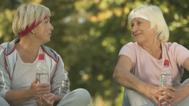 Two Female Friends Sportswear Talking Workout Sitting Park — Stock Video