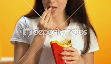 Genç kadın yağlı patates kızartması fast food restoranında, sağlıksız yemek yeme