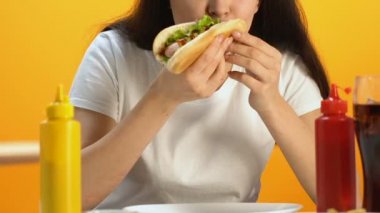 Aç erkek lezzetli sosisli sandviç, ısırma lezzetli fast food yemek, yakın çekim zevk