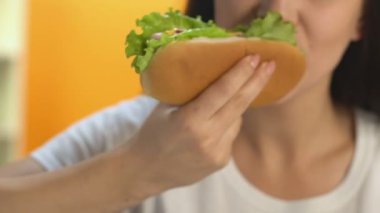 Yüksek kalorili sosisli sandviç yeme öğle vakti, yağlı fast food snack, diyet sırasında kadın