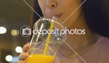 Gülümseyen kadın büyük plastik bardaktan taze portakal suyu içme öğle yemeği