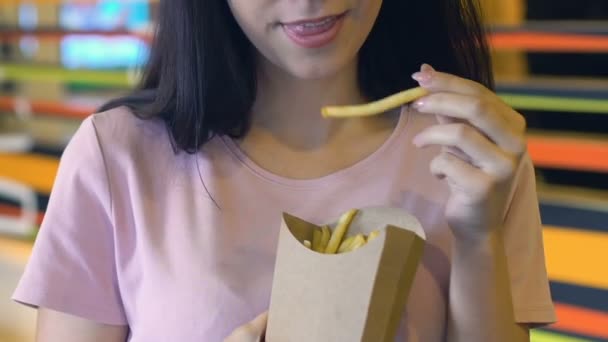 カメラ テイクアウトの食事前にカリカリと塩味のフライド ポテトを食べて幸せな女 — ストック動画